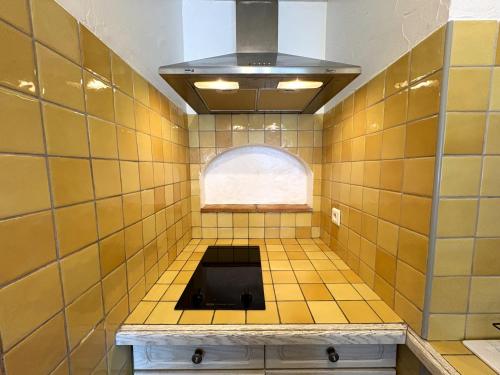 ein gelb gefliestes Bad mit einem Waschbecken und einem Fenster in der Unterkunft Studio cosy à 200m de la plage Parking & Wi-Fi in Bormes-les-Mimosas