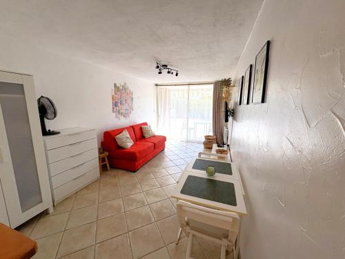 ein Wohnzimmer mit einem roten Sofa und einem Tisch in der Unterkunft Studio cosy à 200m de la plage Parking & Wi-Fi in Bormes-les-Mimosas