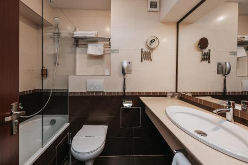 a bathroom with a toilet and a sink and a phone at Grand Hotel Napoca in Cluj-Napoca
