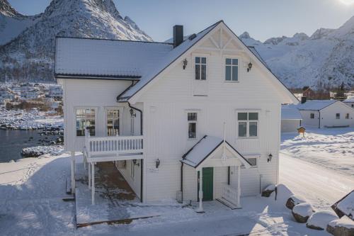 a white house in the snow with a mountain at Mefjord Brygge in Mefjordvær