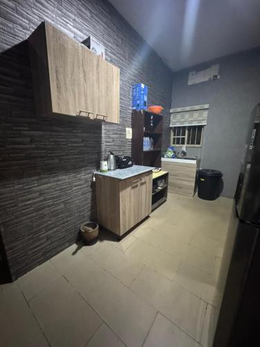 a kitchen with wooden cabinets and a brick wall at Barry's Hilton extension in Abuja