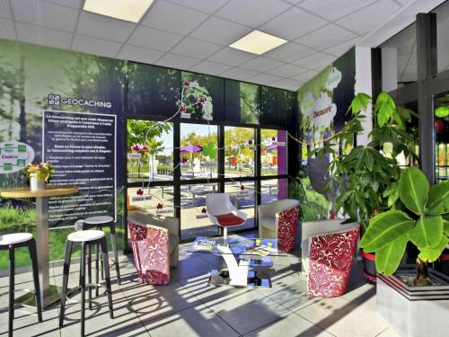 a rendering of a restaurant with tables and stools at ibis Styles Castres in Castres