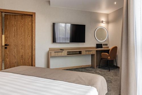a hotel room with a bed and a desk with a television at Silver Apart in Truskavets