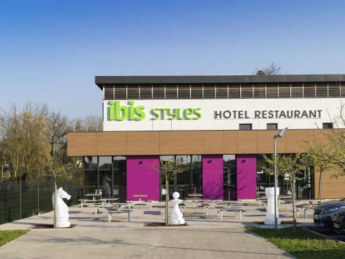 a building with a lot of tables and pink doors at ibis Styles Castres in Castres