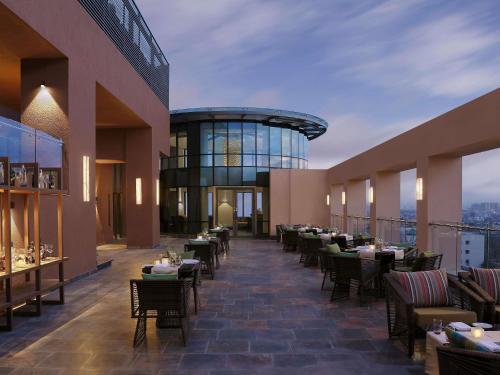 a restaurant with tables and chairs on a balcony at Novotel Lucknow Gomti Nagar in Lucknow