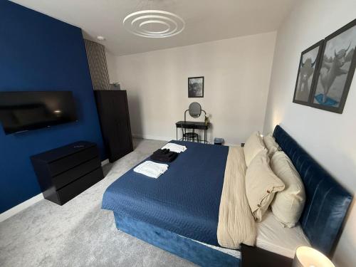 a bedroom with a blue bed and a tv at Above Hotels in Burnley