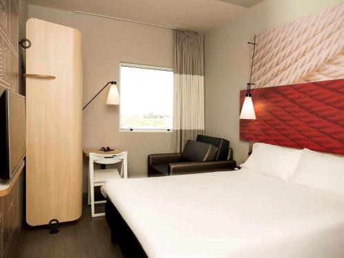 a hotel room with a bed and a chair at ibis Paranagua in Paranaguá