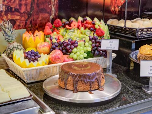 a cake on a plate in front of a tray of fruit at ibis Paranagua in Paranaguá