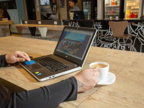 a person sitting at a table with a laptop and a cup of coffee at ibis Paranagua in Paranaguá