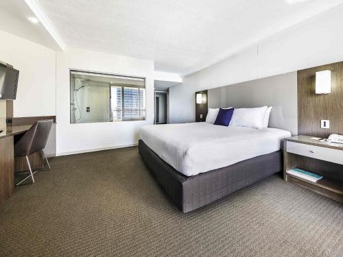 a hotel room with a large bed and a desk at Novotel Surfers Paradise in Gold Coast