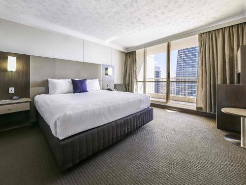 a hotel room with a large bed and a large window at Novotel Surfers Paradise in Gold Coast