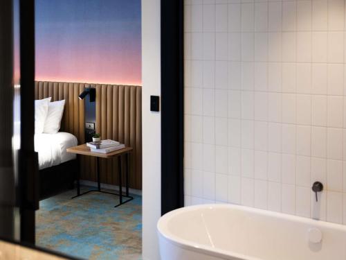 a bathroom with a tub and a bedroom with a bed at Novotel Surfers Paradise in Gold Coast