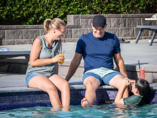a man and woman sitting next to a child in a swimming pool at Novotel Surfers Paradise in Gold Coast