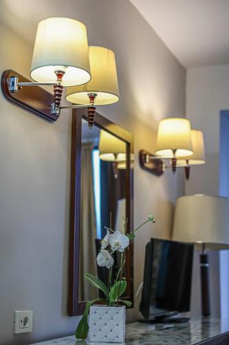 a room with two lights and a vase with flowers on a desk at Grand Hotel Napoca in Cluj-Napoca