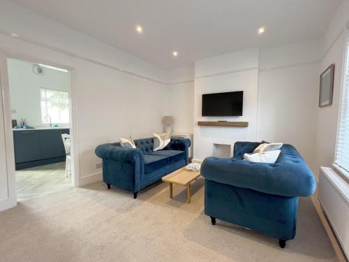 a living room with two blue chairs and a tv at Beach House in Eastbourne