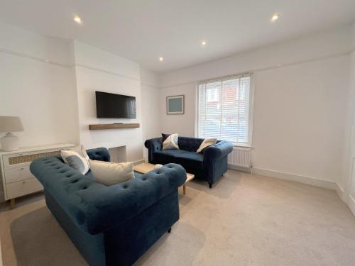 a living room with two blue couches and a tv at Beach House in Eastbourne