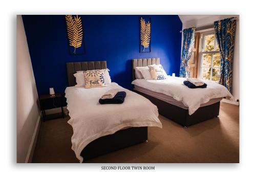 two beds in a room with blue walls at Clarefoot Cottage in Moffat