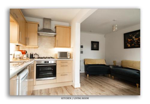 a kitchen and a living room with a couch at Clarefoot Cottage in Moffat