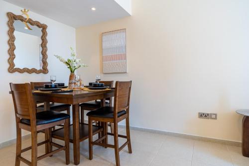 a dining room table with chairs and a mirror at Modern 2BR Haven - Chic Serene Escape in Abu Dhabi