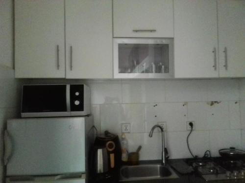a kitchen with white cabinets and a microwave at Citycomfortluanda in Luanda