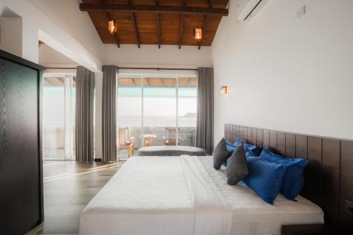 a bedroom with a large bed with blue pillows at New Summer Garden in Unawatuna