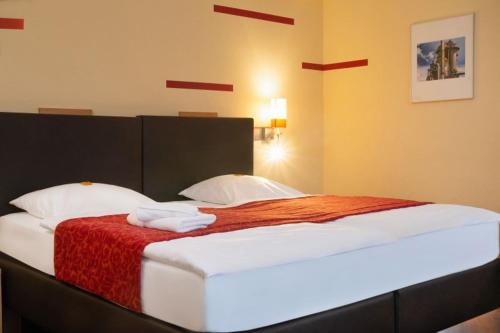 a bedroom with a large bed with a red blanket at Hotel NeuHaus in Dortmund