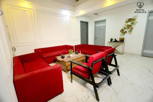 a living room with red couches and a table at Hotel Wedlock in Gurgaon
