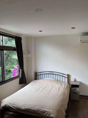 a bedroom with a white bed and a window at The Little Garden in Miyazaki