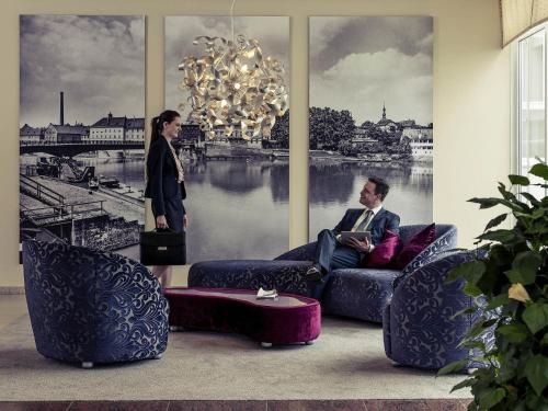 シュヴァインフルトにあるMercure Hotel Schweinfurt Maininselの部屋の中で女性と一緒にソファに座っている男性