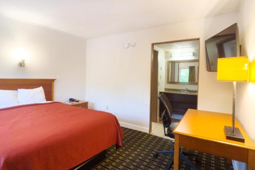 a hotel room with a bed and a desk and a mirror at Tennessee Mountain Lodge Riverside by OYO in Pigeon Forge