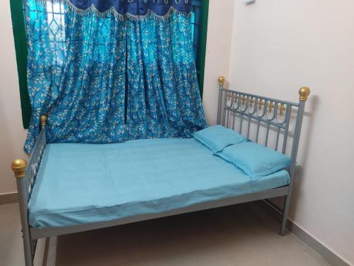 a bed with blue sheets and a curtain at Arunachala Home Stay - Closest to Temple in Tiruvannāmalai