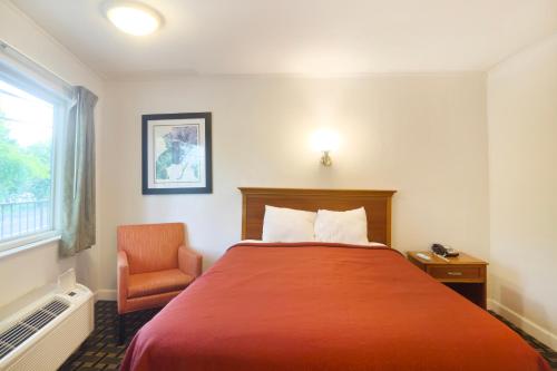 a hotel room with a red bed and a chair at Tennessee Mountain Lodge Riverside by OYO in Pigeon Forge