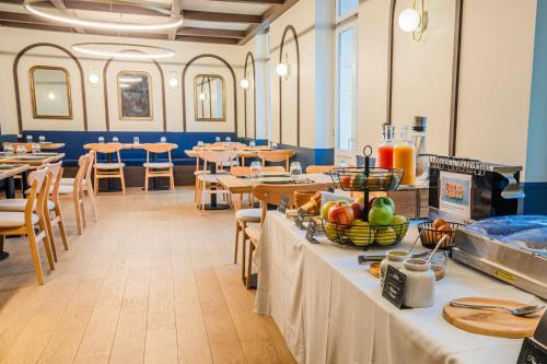 a dining room with tables and chairs and food on tables at Hôtel de France - Beaune in Beaune