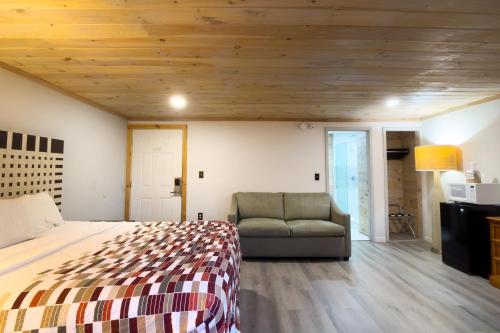 a bedroom with a bed and a couch and wooden ceilings at Tennessee Mountain Lodge Riverside by OYO in Pigeon Forge
