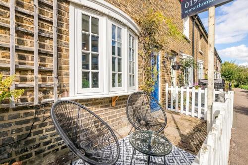 two metal benches sitting outside of a building at Riverside Cottage Retreat Hertford Town Sleeps 6 in Hertford