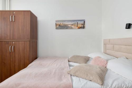 ein Schlafzimmer mit einem Bett und einem Holzschrank in der Unterkunft Piękny Słoneczny Apartament Blisko Plaży dla 4 Osób by Noclegi Renters in Przymorze