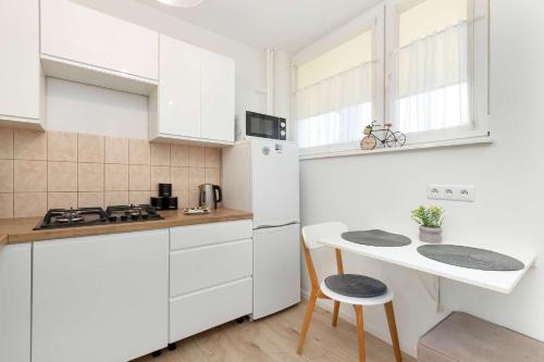 eine weiße Küche mit einem Tisch und einem weißen Kühlschrank in der Unterkunft Piękny Słoneczny Apartament Blisko Plaży dla 4 Osób by Noclegi Renters in Przymorze