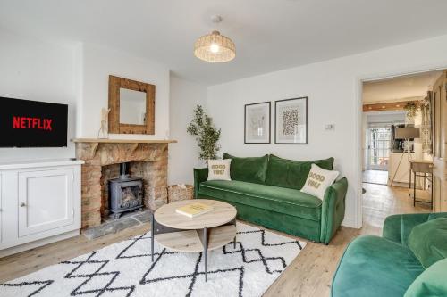 a living room with a green couch and a fireplace at Riverside Cottage Retreat Hertford Town Sleeps 6 in Hertford