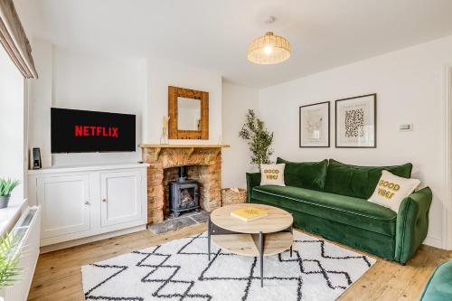 a living room with a green couch and a fireplace at Riverside Cottage Retreat Hertford Town Sleeps 6 in Hertford