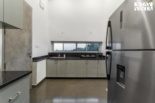 a kitchen with a stainless steel refrigerator and a window at StayVista at Lazy Mango with Bonfire, Bathtub in Hyderabad