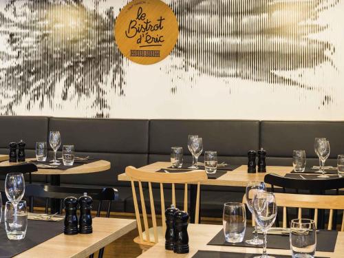 a restaurant with tables and chairs with wine glasses at ibis Styles Rouen Val De Reuil in Val de Reuil