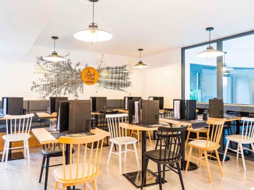 a restaurant with wooden tables and chairs and windows at ibis Styles Rouen Val De Reuil in Val de Reuil