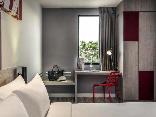 a bedroom with a bed and a desk with a red chair at ibis Bangkok IMPACT in Nonthaburi
