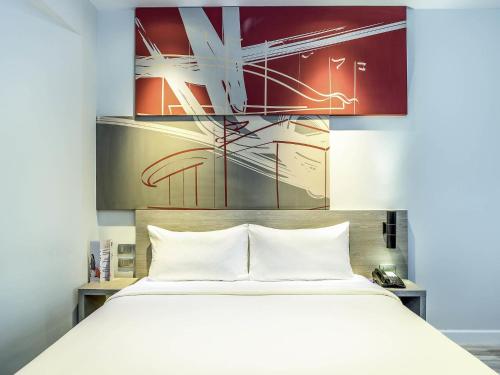 a bedroom with a white bed and a painting at ibis Bangkok IMPACT in Nonthaburi