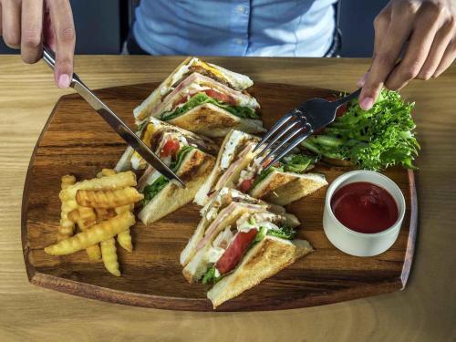 a wooden plate with a sandwich and french fries at ibis Bangkok IMPACT in Nonthaburi