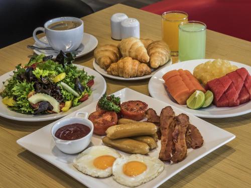 a table with plates of breakfast foods and drinks at ibis Bangkok IMPACT in Nonthaburi
