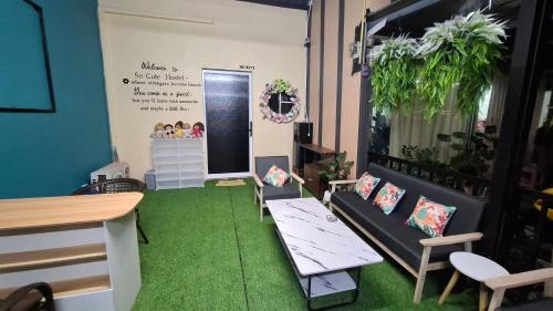 a room with green carpet and a table and chairs at So Cute Hostel, Kai Bae, Koh Chang in Trat