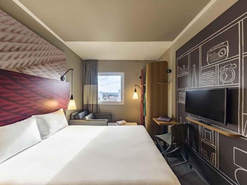 a hotel room with a large bed and a tv at ibis Jacarei in Jacareí
