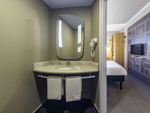 a bathroom with a sink and a mirror at ibis Jacarei in Jacareí