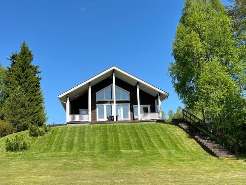 a house on a hill with a large grassy field at Rantatähti Villa in Syöte